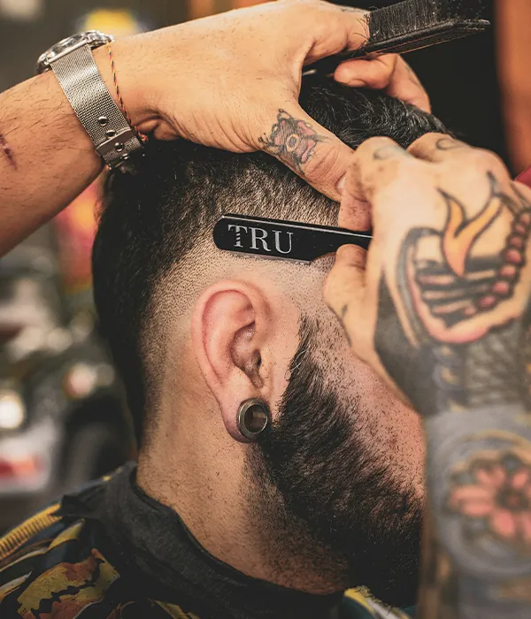 A barber shaping a client's hairline.